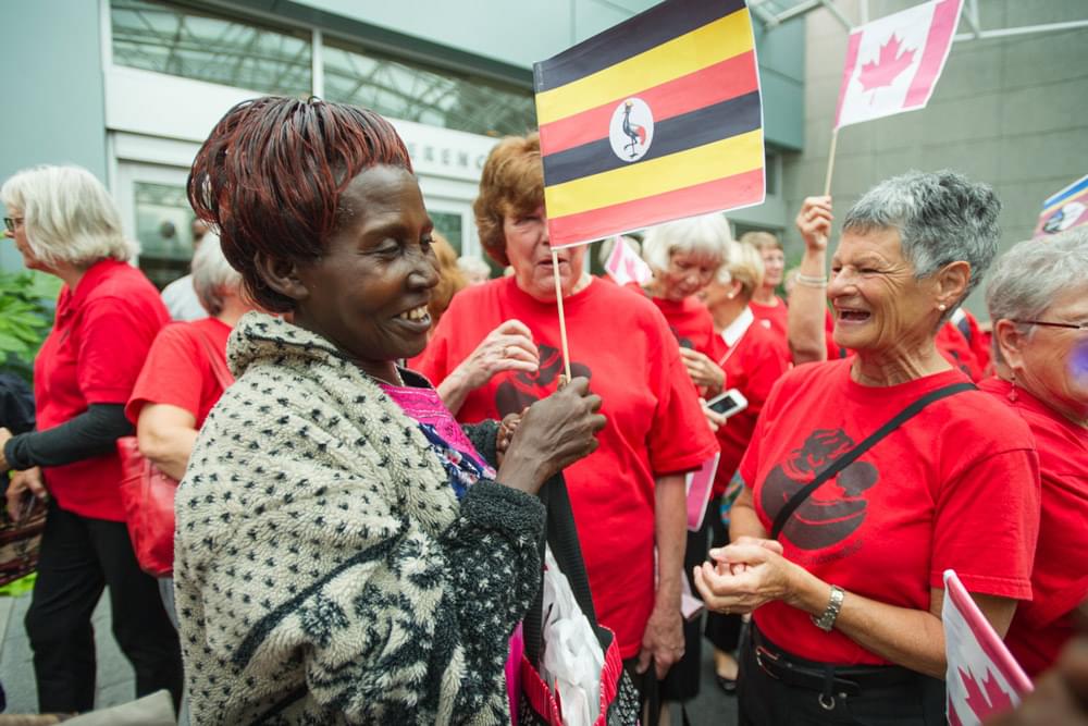  african and canadian grandmothers smiling and gathering outside with flags
