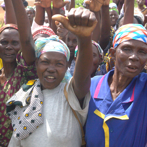 Women gathered in a group with their fists raised in solidarity at PENAF in Kenya